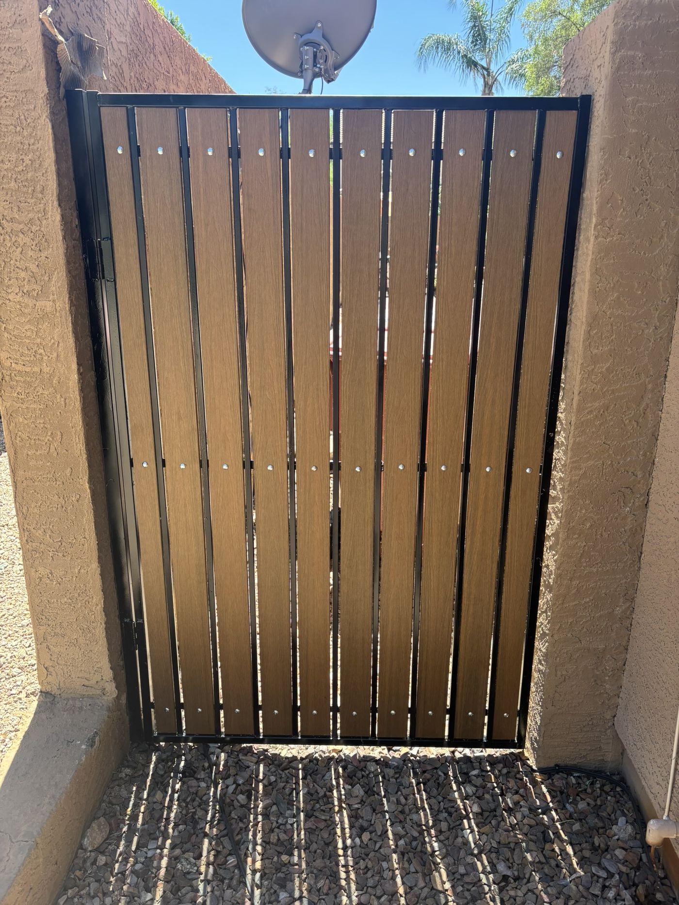 Gate after refurbishment with warm brown woodgrain slats and fresh black frame